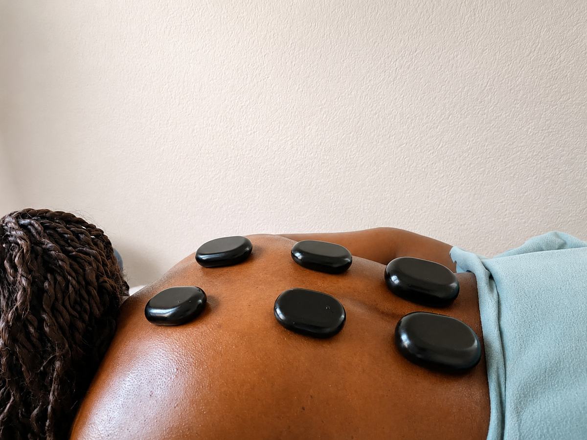 Hot-Stone-Massage mit warmen Basaltsteinen auf dem Rücken